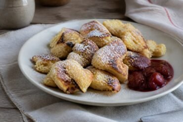 Austrian kaiserschmarrn pancake pieces with powdered sugar and plum compote.