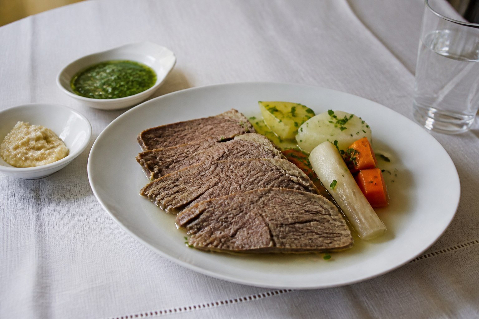 Austrian Tafelspitz sliced with root vegetables, broth, chive sauce, and apple horseradish.