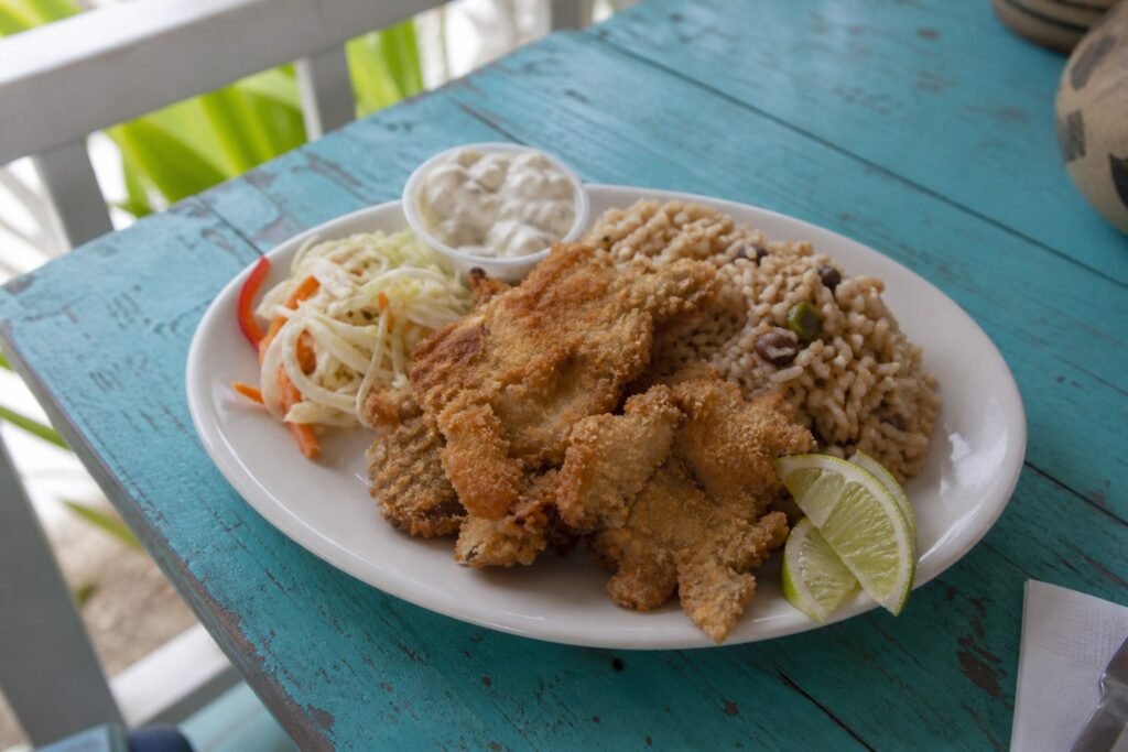 Bahamian cracked conch with peas and rice, slaw, tartar sauce, and lime.