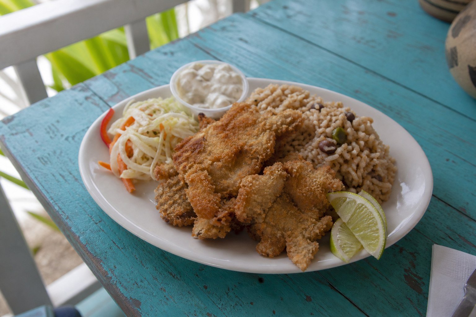 Bahamian cracked conch with peas and rice, slaw, tartar sauce, and lime.