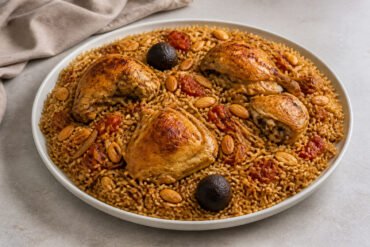 Bahraini chicken machboos with spiced rice, roasted chicken, almonds, and dried lime.