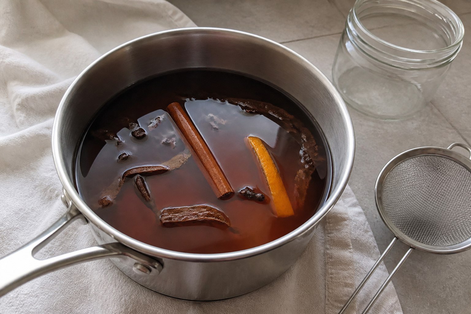 Mauby bark, cinnamon, cloves, and orange peel steeping in a saucepan.