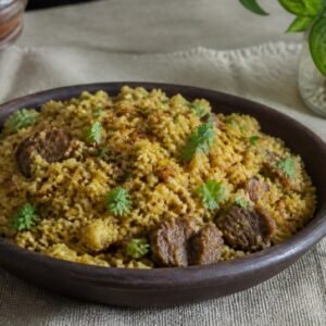 Bangladeshi bhuna khichuri with golden rice, moong dal, beef, fried onion, and cilantro.