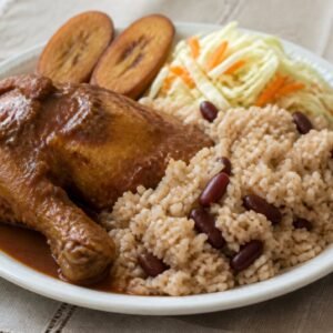 Belizean red recado stew chicken served with coconut rice and beans, slaw, and plantain.
