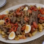Bolivian pique macho platter with beef, sausage, potatoes, onion, tomato, locoto, and egg.