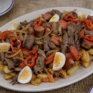 Bolivian pique macho platter with beef, sausage, potatoes, onion, tomato, locoto, and egg.