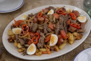 Bolivian pique macho platter with beef, sausage, potatoes, onion, tomato, locoto, and egg.