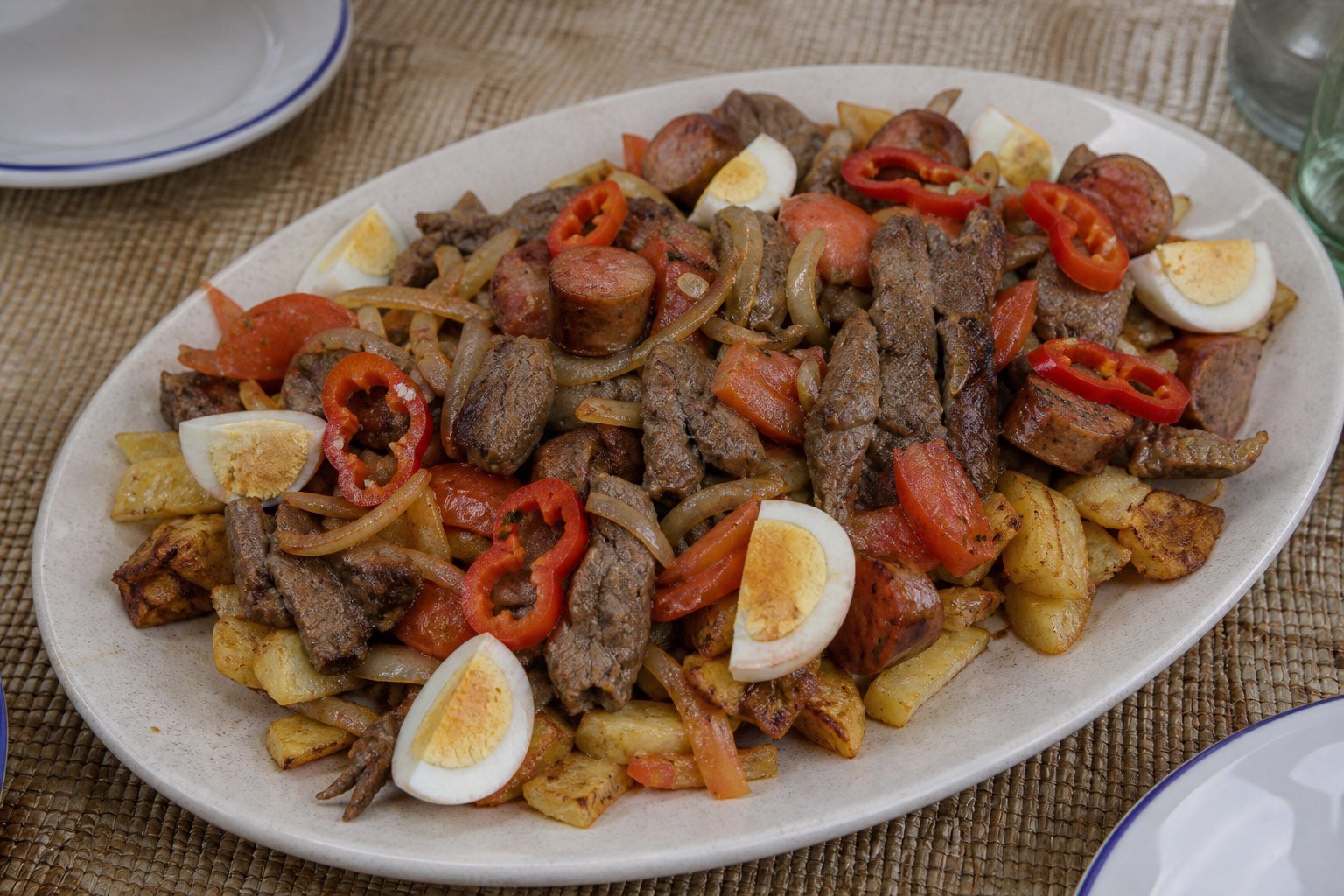Bolivian pique macho platter with beef, sausage, potatoes, onion, tomato, locoto, and egg.