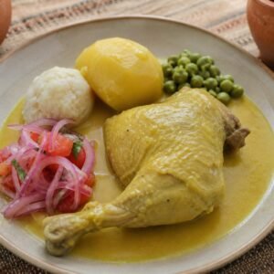 Bolivian sajta de pollo with yellow chile chicken, potato, tunta, peas, and onion-tomato sarza.