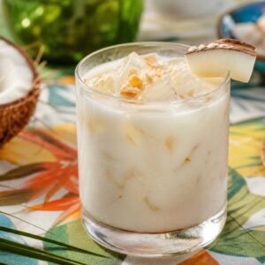 Creamy Brazilian batida de coco cocktail over ice in a chilled glass with coconut garnish.