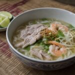 Cambodian kuy teav with pork, shrimp, rice noodles, bean sprouts, herbs, and clear broth.