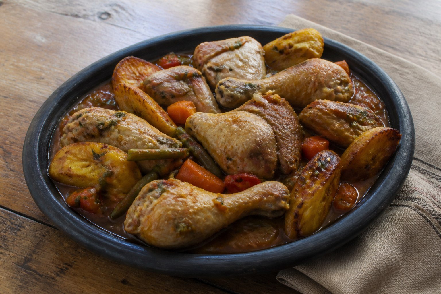 Cameroonian Poulet DG with bone-in chicken, fried plantain, and vegetables.