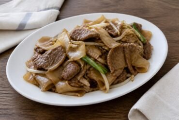 Cantonese beef chow fun with broad rice noodles, bean sprouts, and scallions.