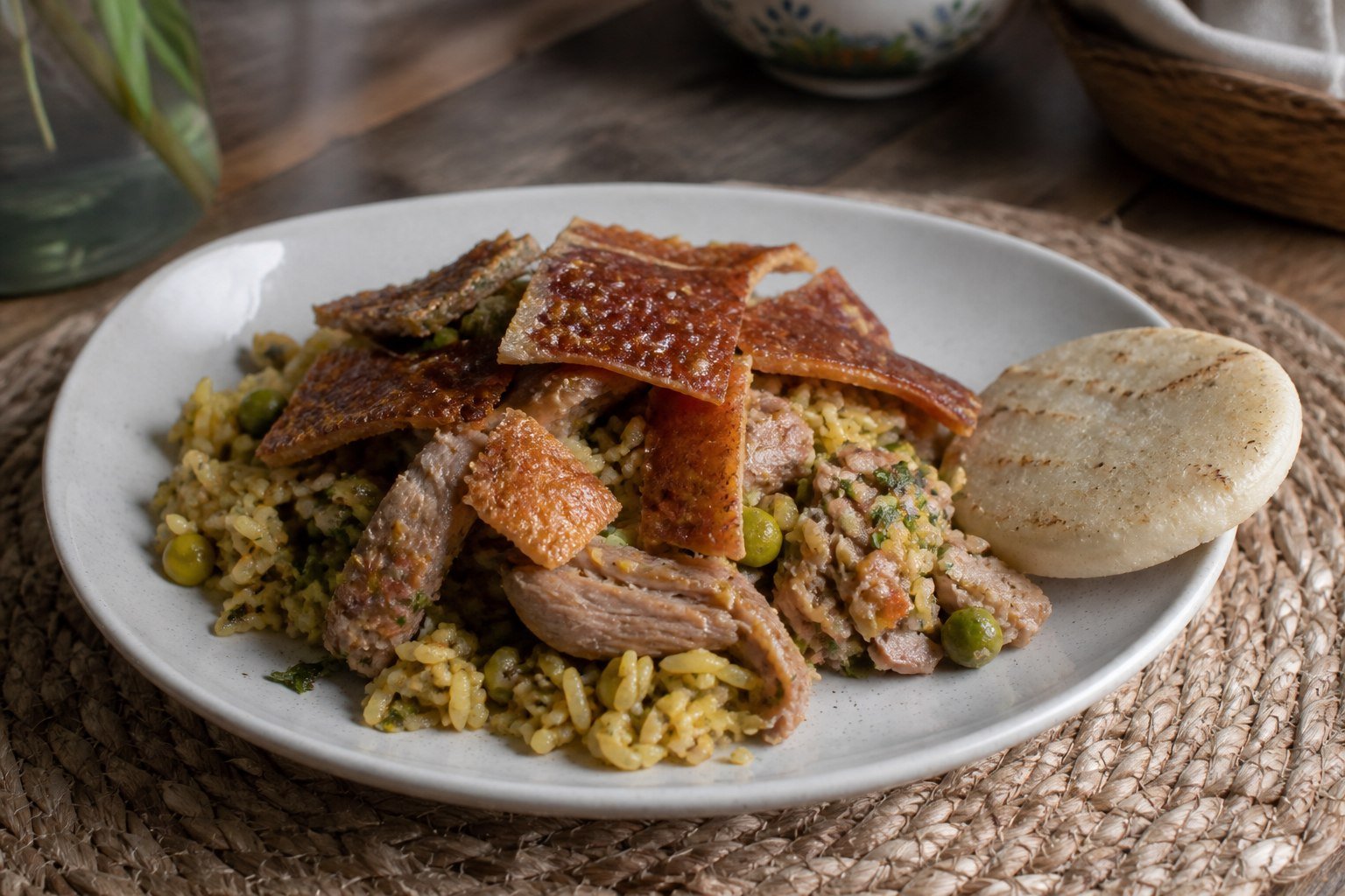 Colombian lechona Tolimense with seasoned rice, peas, roast pork, crisp skin, and arepa.