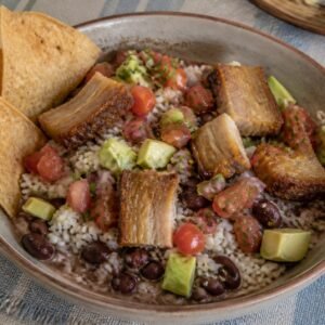 Costa Rican chifrijo with rice, red beans, pork-belly chicharron, pico de gallo, avocado, and chips.