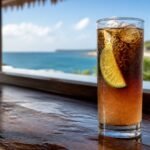 Dark n Stormy cocktail with dark rum layered over ginger beer, ice, bubbles, and a lime wedge.