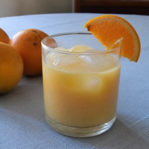 Dominican morir sonando, a creamy orange and milk drink served cold with ice and an orange slice.