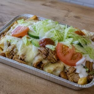 Dutch kapsalon layered with fries, chicken, Gouda, salad, garlic sauce, and sambal.