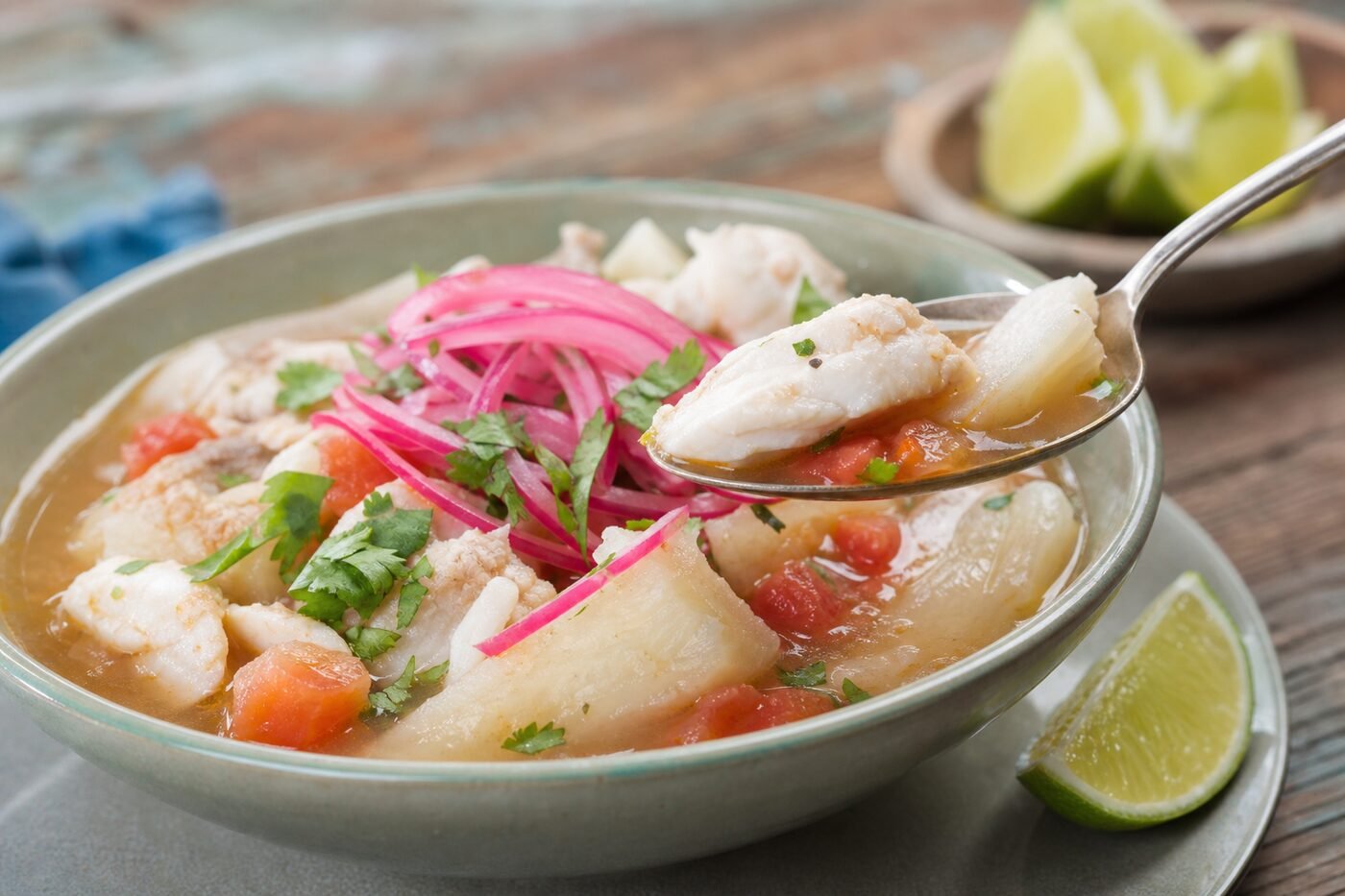 A spoonful of Ecuadorian fish and yuca soup with pickled onion and lime.