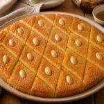 Golden Egyptian basbousa semolina cake cut into almond-topped diamonds.
