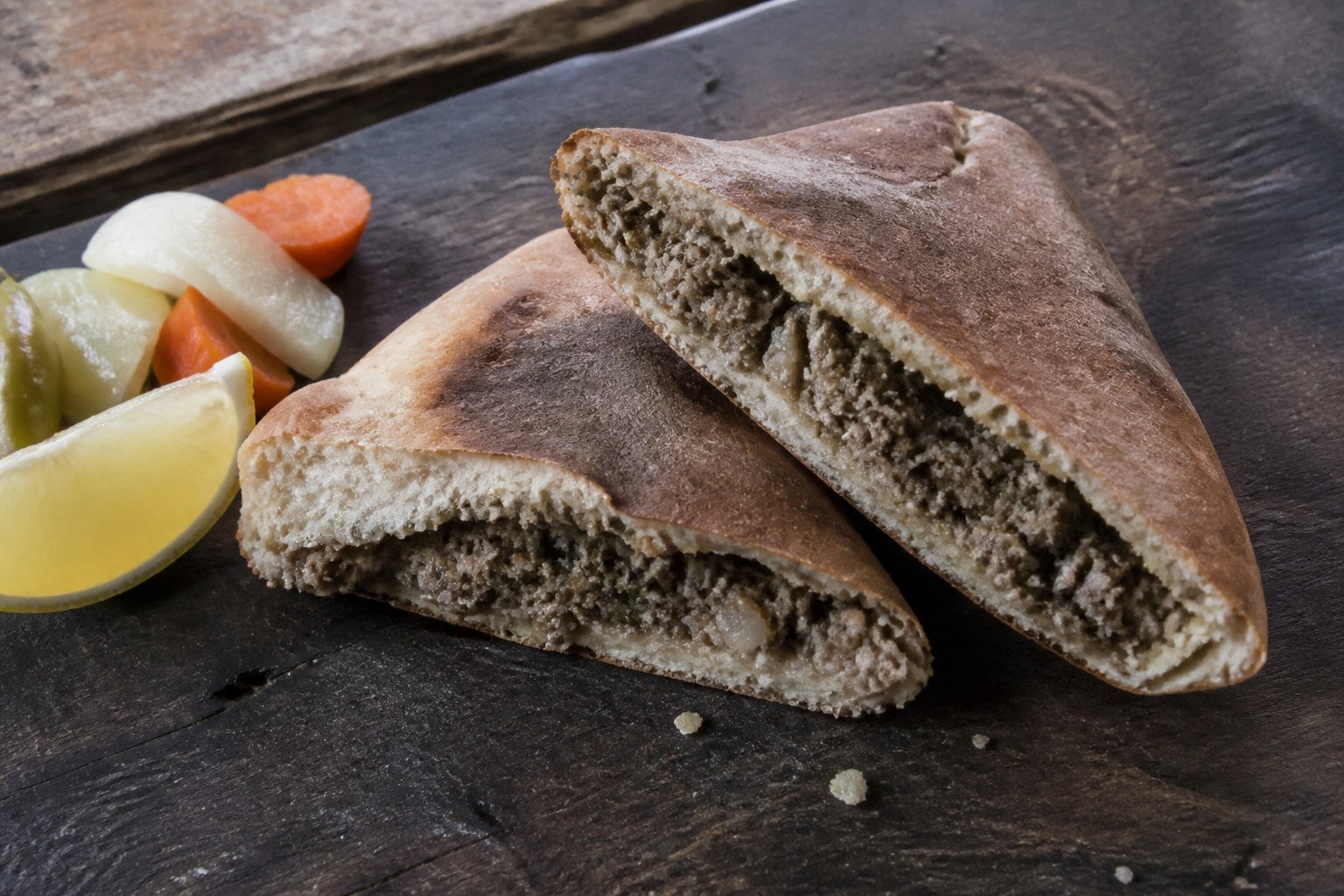 Cut Egyptian hawawshi showing the seasoned beef filling inside baked flatbread.