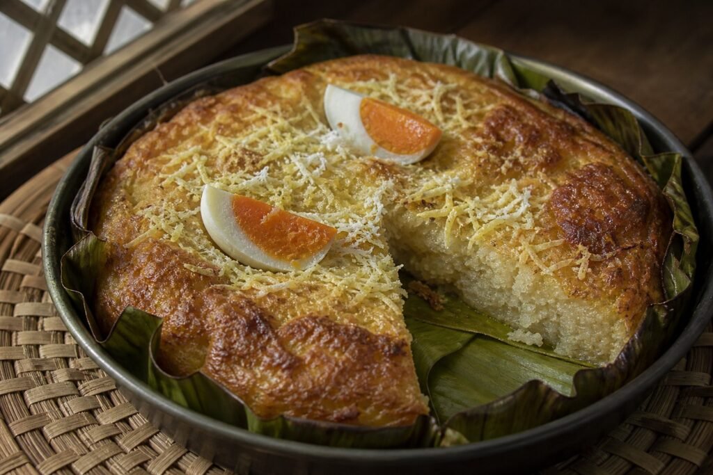 Filipino bibingka rice cake baked on banana leaf with salted egg, cheese, and grated coconut.