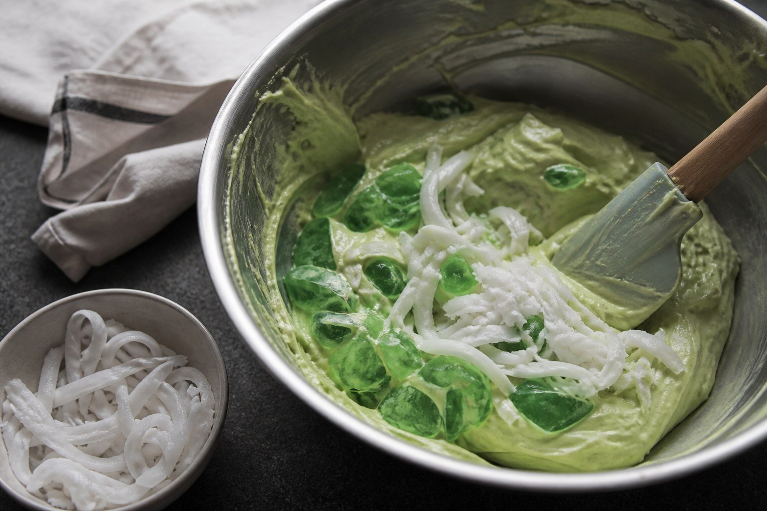 Pandan jelly and young coconut being folded into cream for buko pandan.