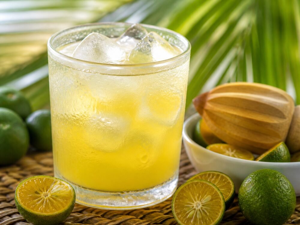 A chilled glass of calamansi juice with condensation and fresh citrus.