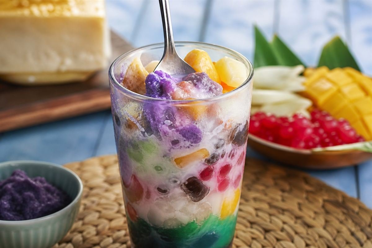 A spoon mixing the colorful shaved-ice layers of Filipino halo-halo.