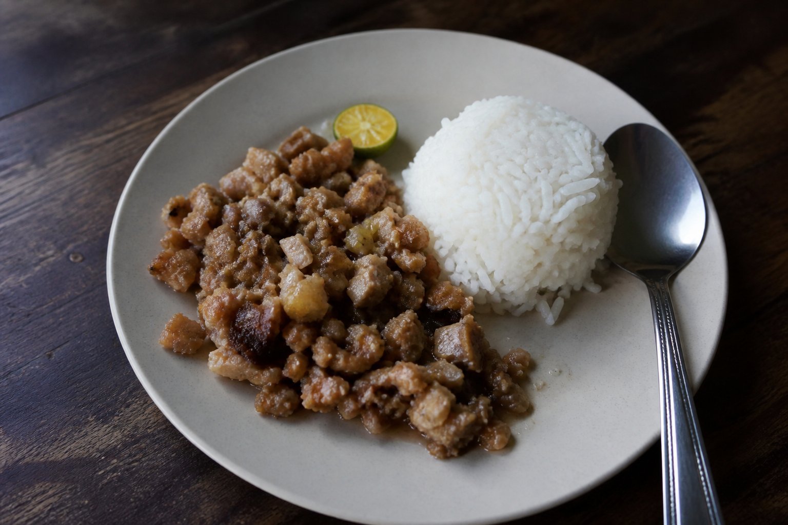 A home-style serving of Filipino pork sisig with steamed rice and calamansi.