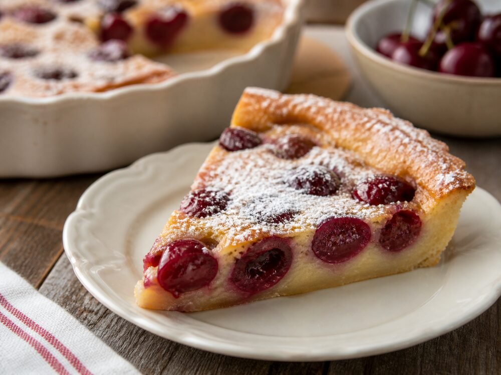 A slice of cherry clafoutis showing its soft custardy center and baked cherries.