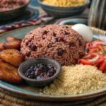 Ghanaian waakye rice and beans served with fried plantain, egg, gari, salad, and shito.