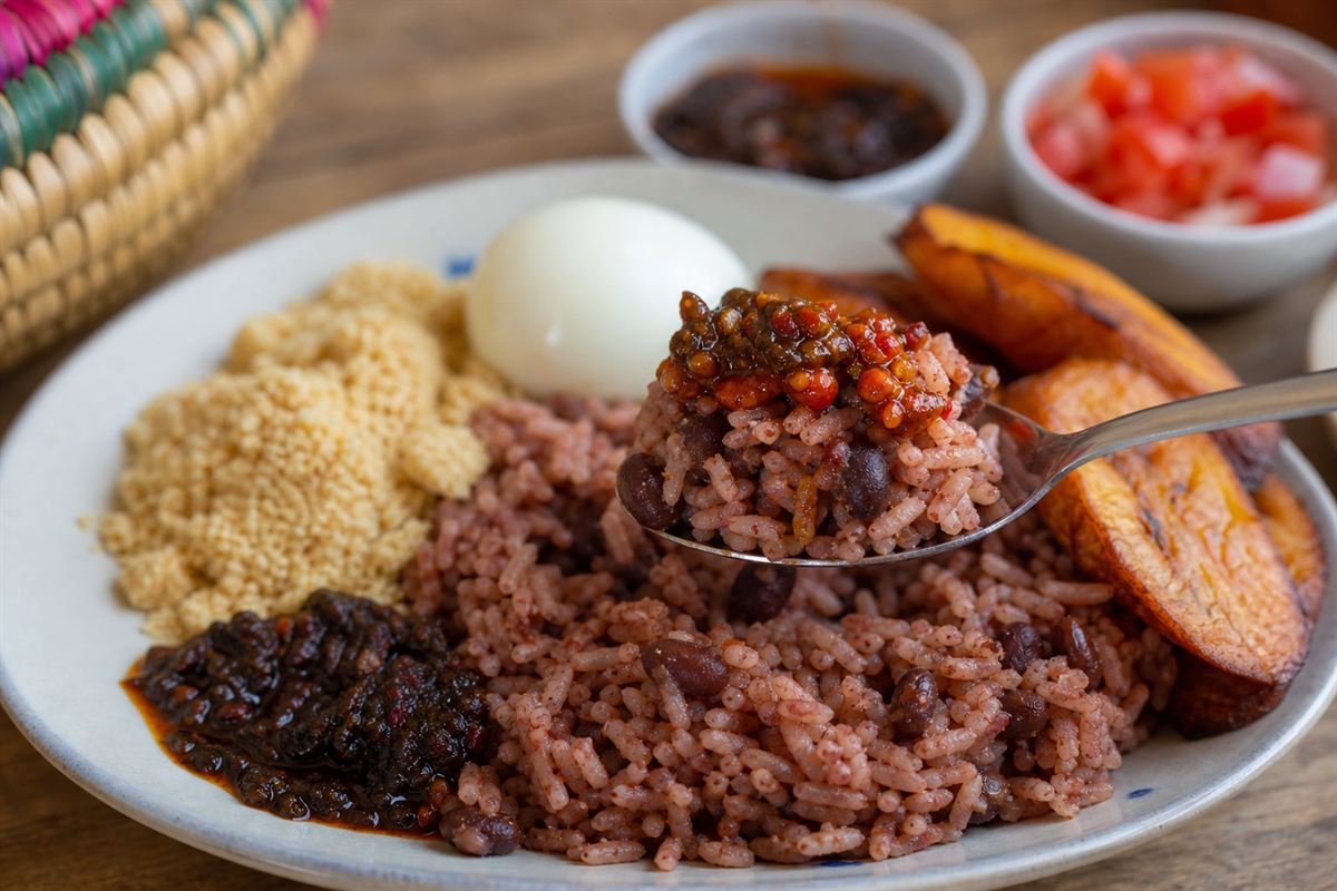 A spoonful of Ghanaian waakye rice and beans with plantain, egg, and pepper sauce.