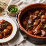 Greek beef stifado with pearl onions in a rich tomato and red wine sauce.