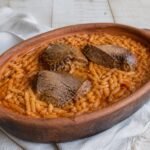 Greek giouvetsi with tomato-braised beef, orzo, and grated cheese in terracotta.