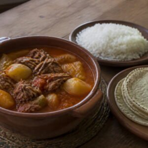 Guatemalan hilachas with shredded beef and potatoes beside rice and tortillas.