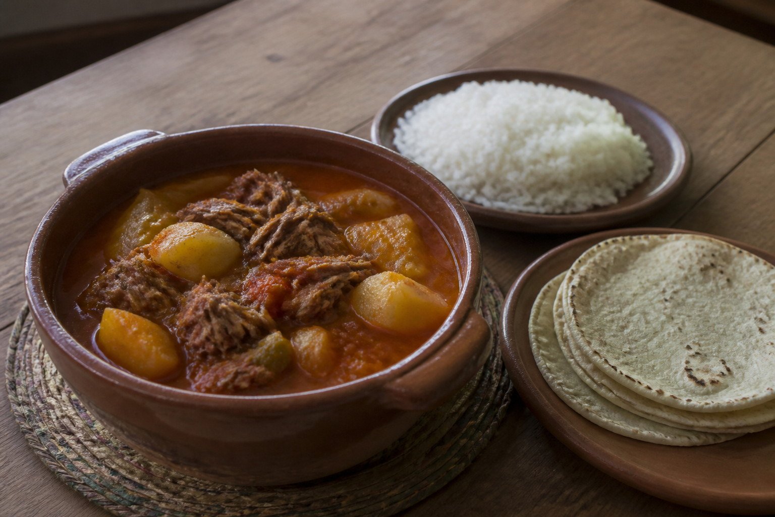 Guatemalan hilachas with shredded beef and potatoes beside rice and tortillas.