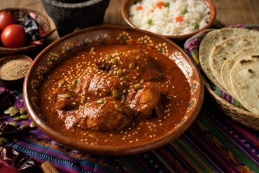 Guatemalan pepián de pollo in a rich roasted chile and seed sauce with rice and corn tortillas.