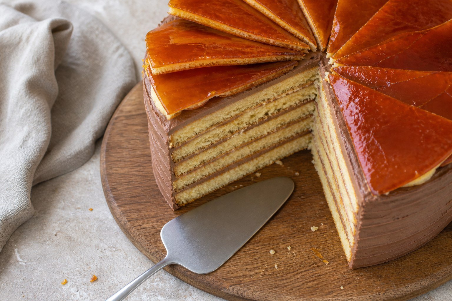 Whole Hungarian Dobos torte with a slice removed and caramel wedges arranged on top.