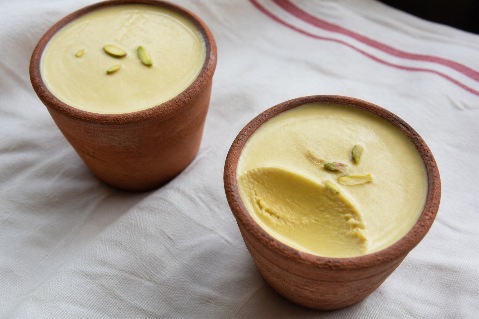 Indian pistachio kulfi served in clay cups with saffron and cardamom.