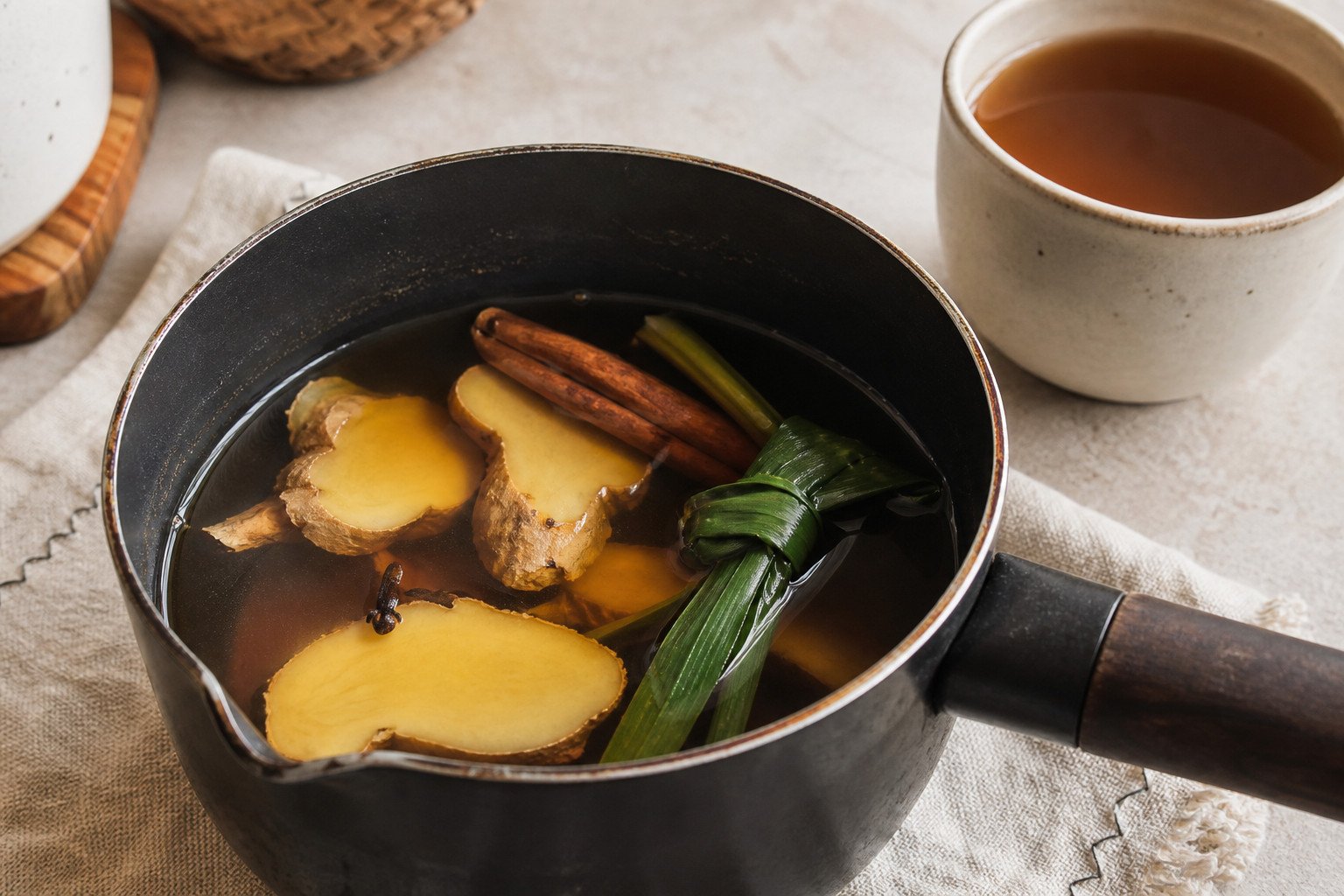 Indonesian bandrek steeping with ginger and spices in a saucepan.