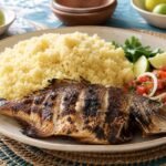 Grilled fish with fluffy Ivorian attiéké cassava couscous, tomato-onion relish, lime, and herbs.