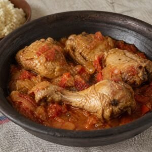 Ivorian kedjenou chicken stew with tomato, peppers, onions, and attieke.