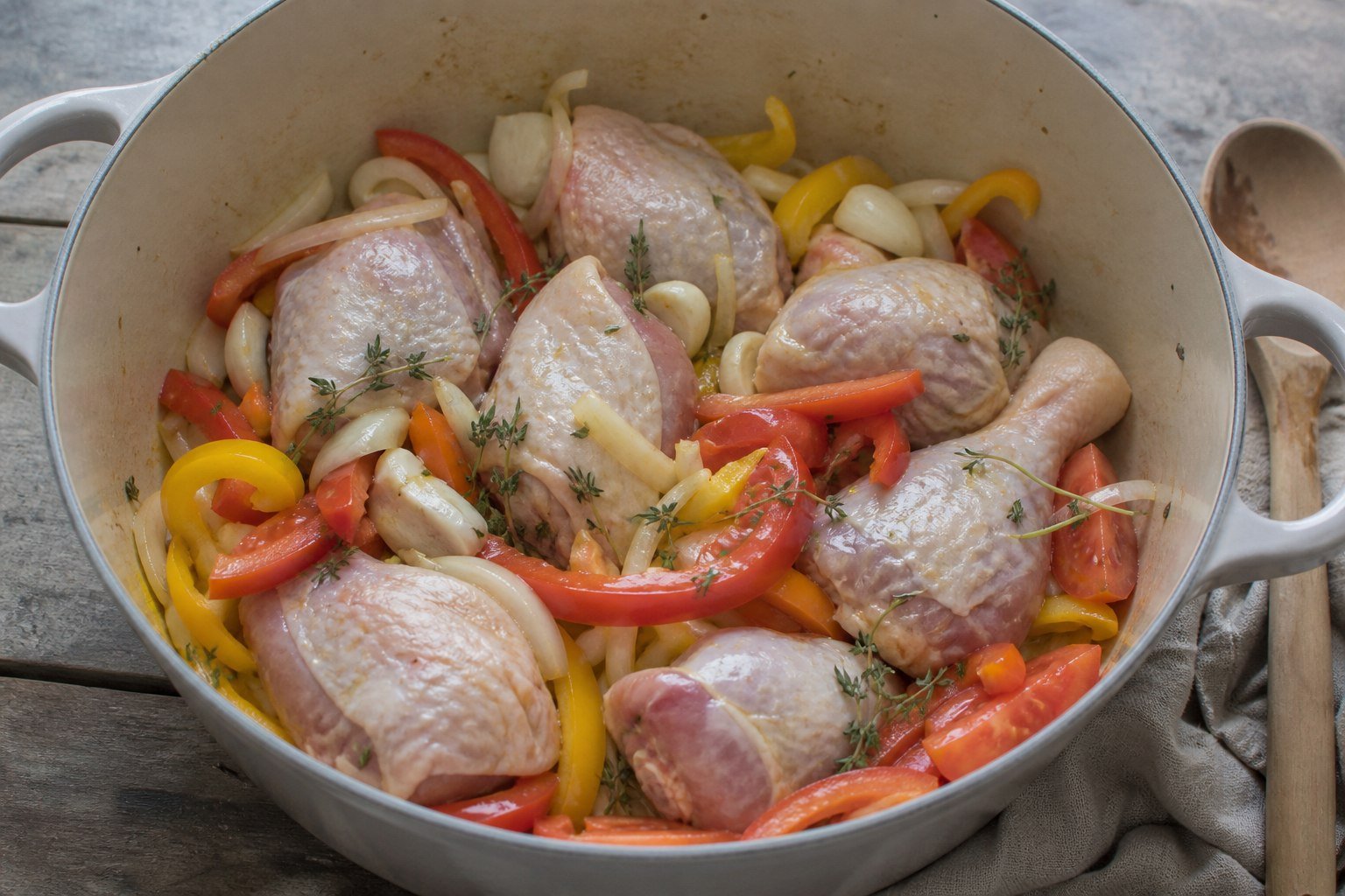 Chicken, tomatoes, onions, and peppers arranged in a pot for Ivorian kedjenou.