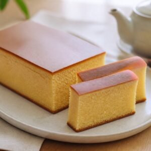 A tall loaf of Japanese castella cake with a smooth brown top and fine golden crumb.