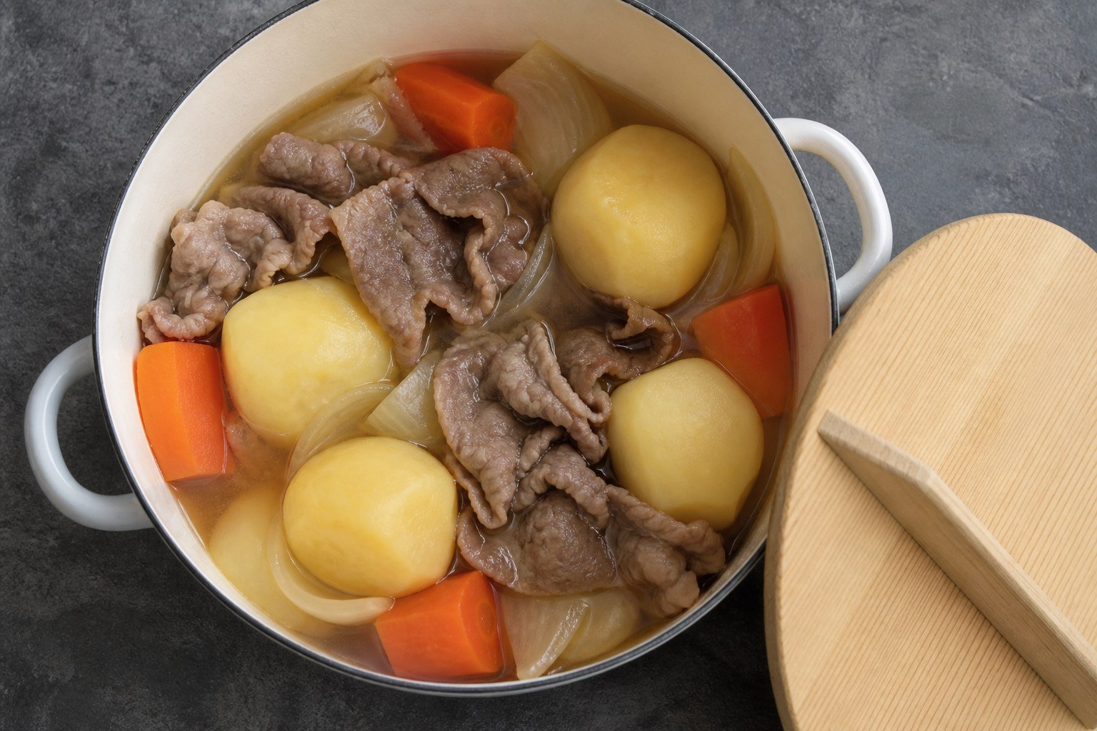 Thin beef and vegetables gently simmering in a pot for Japanese nikujaga.