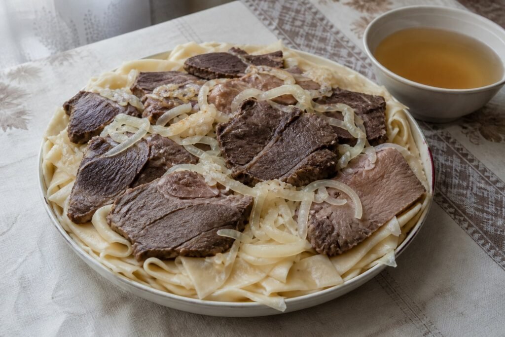 Kazakh beshbarmak with boiled lamb, beef, broad noodles, onions, and broth.