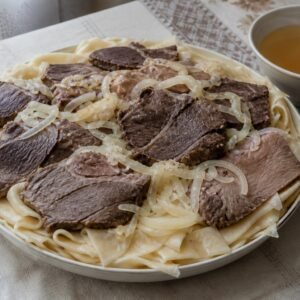 Kazakh beshbarmak with boiled lamb, beef, broad noodles, onions, and broth.