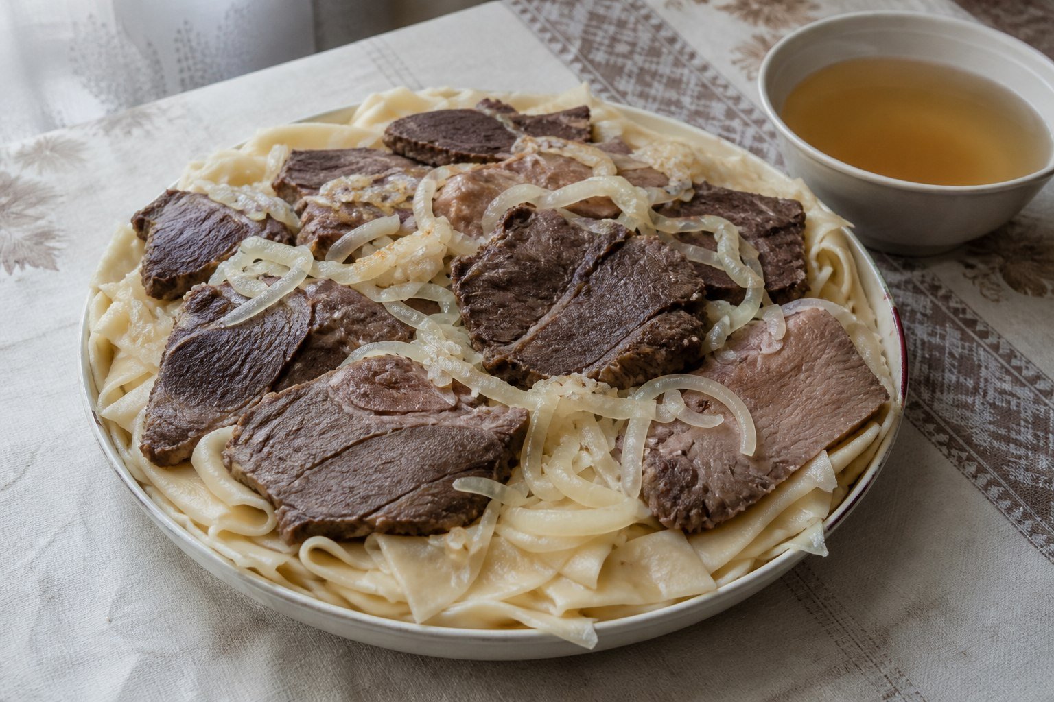 Kazakh beshbarmak with boiled lamb, beef, broad noodles, onions, and broth.