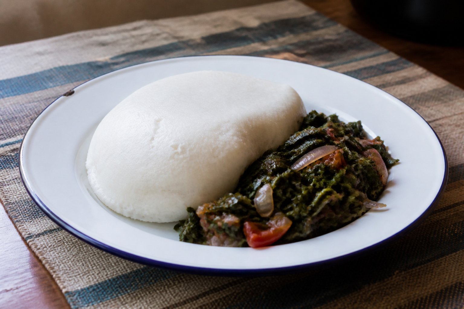 Kenyan maize ugali served with sautéed sukuma wiki, onions, and tomatoes.